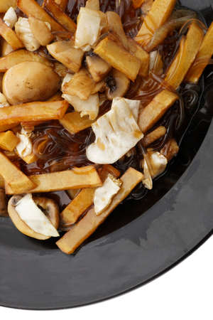 Chinese food. Fried potato chips in sauce in black plate isolated on white. Closeup.
