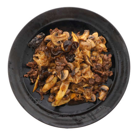 Chinese food. Veal with black and white mushrooms and bamboo shoots in black plate isolated on white. Closeup.の写真素材