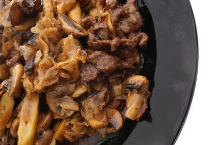 Chinese food. Veal with black and white mushrooms and bamboo shoots in black plate isolated on white. Closeup.の写真素材
