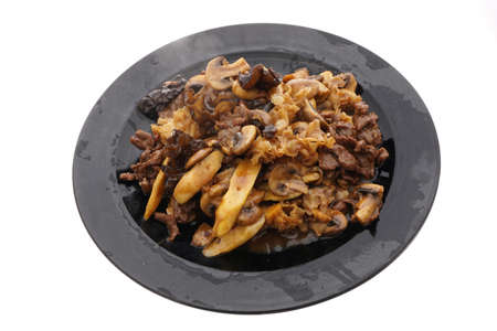 Chinese food. Veal with black and white mushrooms and bamboo shoots in black plate isolated on white. Closeup.の写真素材