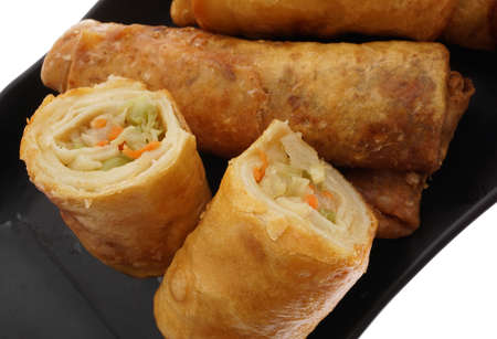 Chinese food. Vegetable spring rolls in black plate isolated on white. Closeup.