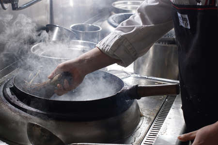 Cleaning wok with wooden sticks and metal wire, Chinese style. Closeup.の写真素材
