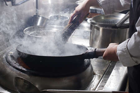 Cleaning wok with wooden sticks and metal wire, Chinese style. Closeup.の写真素材