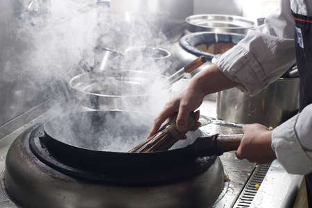 Cleaning wok with wooden sticks and metal wire, Chinese style. Closeup.の写真素材