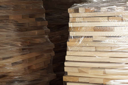 Wooden planks stacked in rows wrapped in plastic foil. Close upの写真素材