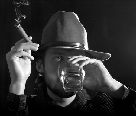 An monochrome image of a bearded man with cigar and glass