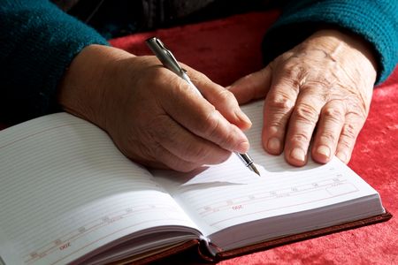 Old hands writing in a notebookの写真素材