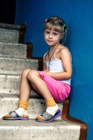 Little girl is sitting on concrete stairsの写真素材