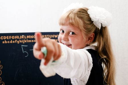 Little girl standing near chalkboard. Writing on it.の写真素材