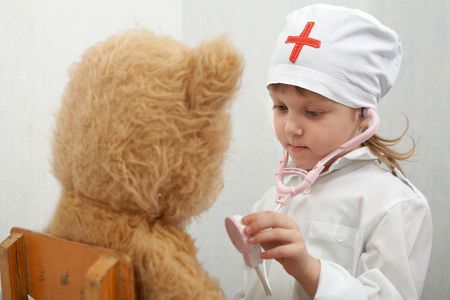 A nice girl with a bear playing a doctorの写真素材