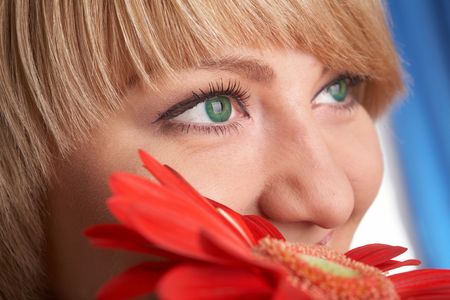 Girl's green eyes and a red flower close-upの写真素材