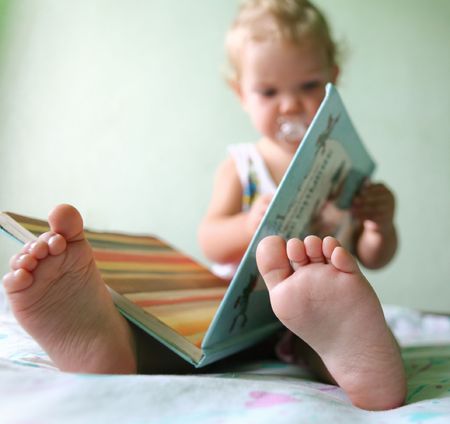 An image of a toddler reading a book. Foots closeupの写真素材