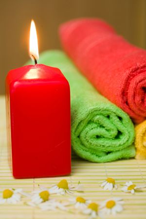 An image of a burning candle, towels and chamomilesの写真素材