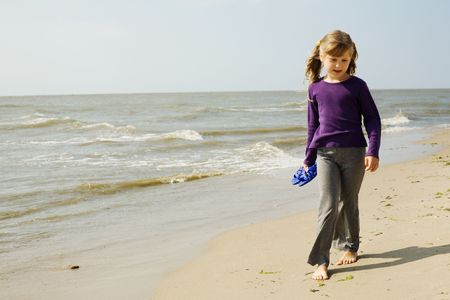 An image of a little girl walking along the seashoreの写真素材