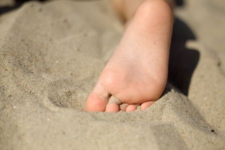 An image of little girl's foot on the sandの写真素材
