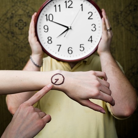 An image of a man with a clock and female handsの写真素材