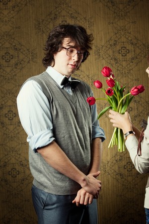 A young man in glasses and red tulipsの写真素材