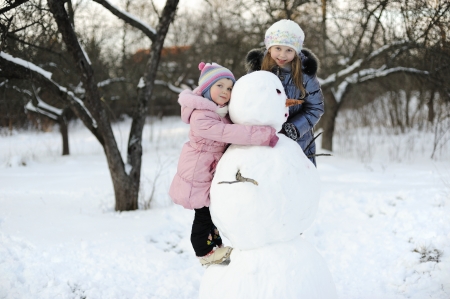 Little girls portrait, happy posing with snowmanの写真素材