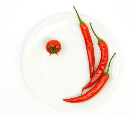 An image of red hot peppers with tomato on plateの写真素材