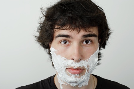 An image of a young man with shaving foam on his faceの写真素材