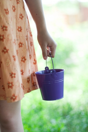 Image of child hands with a bucket in it. Against the backdrop of greeneryの写真素材