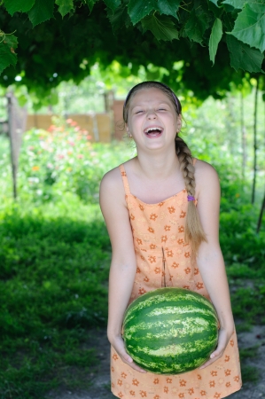 Young girl lifts a heavy watermelonの写真素材