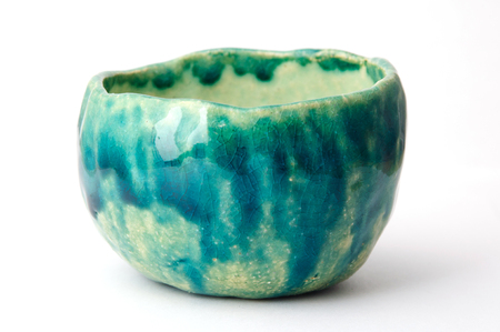Green handmade pottery cup on white backgroundの写真素材