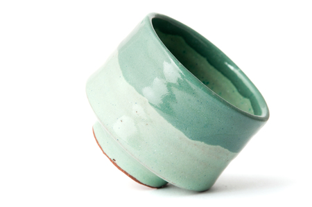 Green handmade pottery cup on white backgroundの写真素材