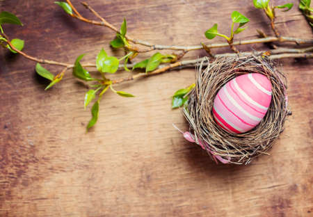 Easter egg in nest on wooden background. Top view