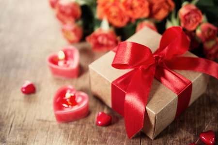 Gift with red bow and heart-shaped candles on the wooden backgroundの写真素材