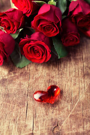 Roses with Small glass heart on wooden backgroundの写真素材