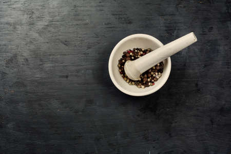Mix of different peppers in a mortar, a top view, black backgroundの写真素材
