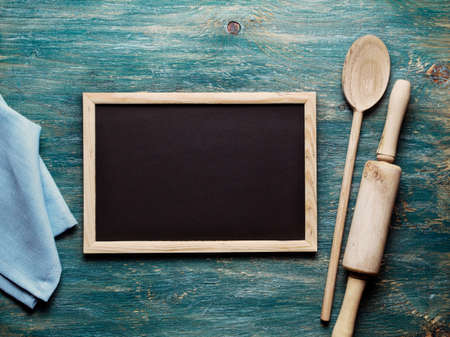 Blank black board on wooden table and kitchen toolsの写真素材