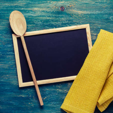 Black chalk board with yellow towel and wooden spoon. Kitchen tools
