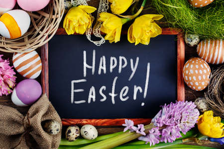 Black board on wooden table with text - Happy Easter. Top view