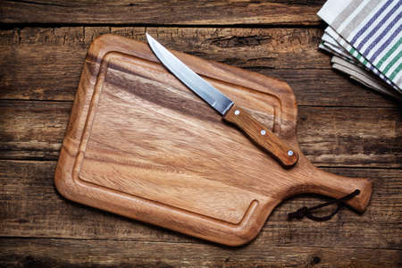 Cutting board and a kitchen knife on old wooden background. Top viewの写真素材