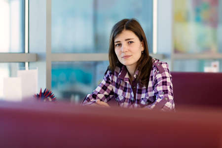Young woman sitting indoor in urban cafe.の写真素材