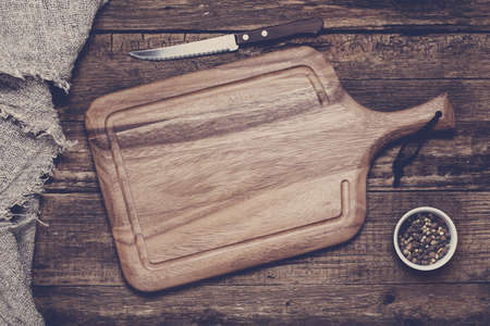 Empty vintage cutting board on old wooden background. Food background concept. Toned imageの写真素材