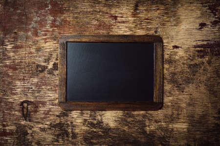 Small wooden framed blank chalkboard on a old dark backgroundの写真素材