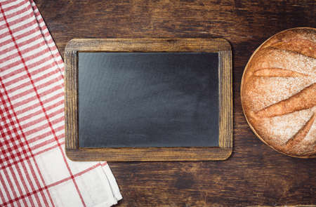 Large loaf of bread and chalkboard on a rustic dark backgroundの写真素材