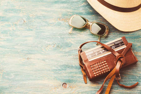 Old retro sunglasses, radio and a hat on a wooden table
