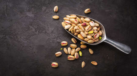 Pistachios in a scoop on a dark background. Food background with copyspaceの写真素材