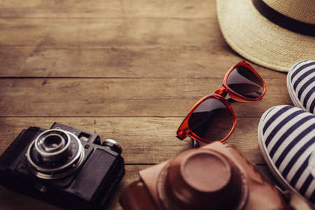 Old camera, sunglasses and sneakers on a wooden floor background.  Free space for text.