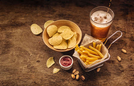 French fries, potato chips and beer on wood backgroundの写真素材
