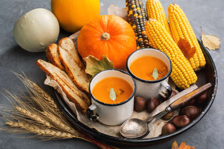 Pumpkin cream soup with crispy croutons in a white vintage mugs. Autumn background