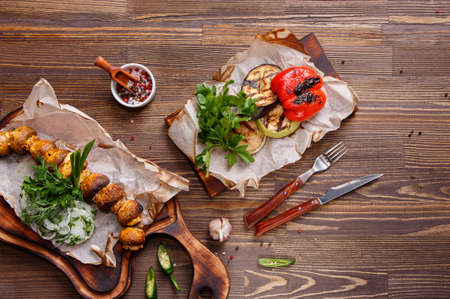 Different food on a wooden table. Grilled vegetables, zucchini, onion and eggplant. Grilled mushrooms with onions and greens. Food background, Top viewの写真素材
