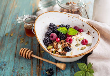 Delicious breakfast with fresh berries and honey on a old wooden table. Healthy breakfast. Selective focusの写真素材