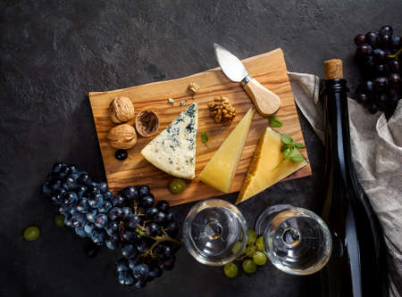 Blue cheese, parmesan, wine and grapes on dark stone background.の写真素材