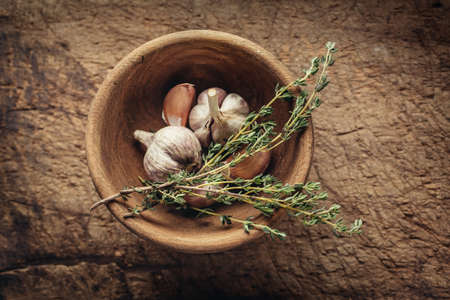 Condiments. Garlic and Fresh Thyme in wooden bowl on a old rustic table.の写真素材