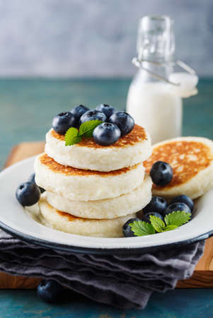 Cottage cheese pancakes with blueberries and milk, homemade traditional Ukrainian and Russian cuisine. Selective focusの写真素材